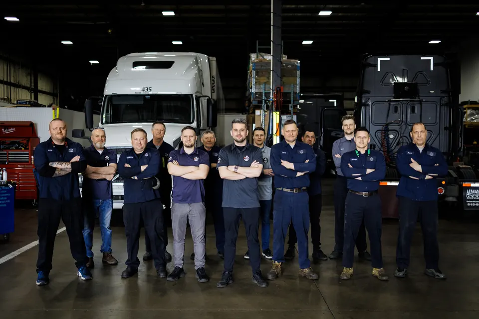 The Truck Clinic crew in the Romeoville shop, in red shirts beside a truck