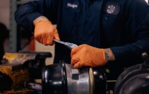 Man with orange gloves working on a truck part