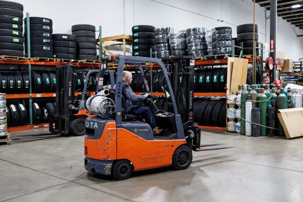 Truck repair parts transported by a man working with a mobile lifter in truck repair shop